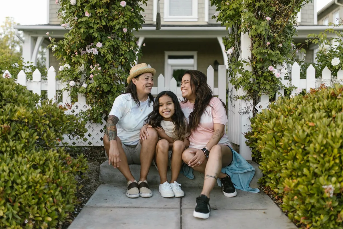 A family sitting on the front walk of their home